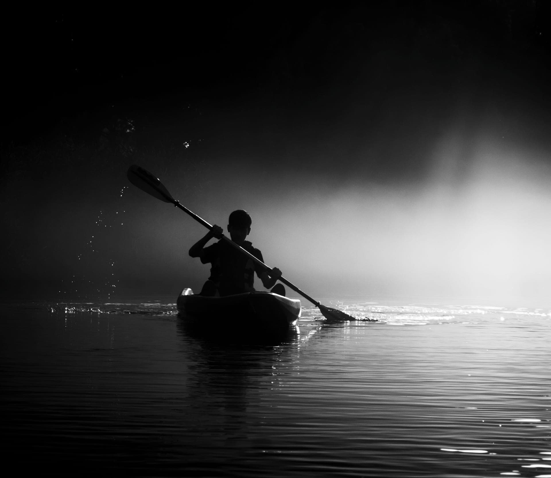 A kayaker paddling through mist at dawn
