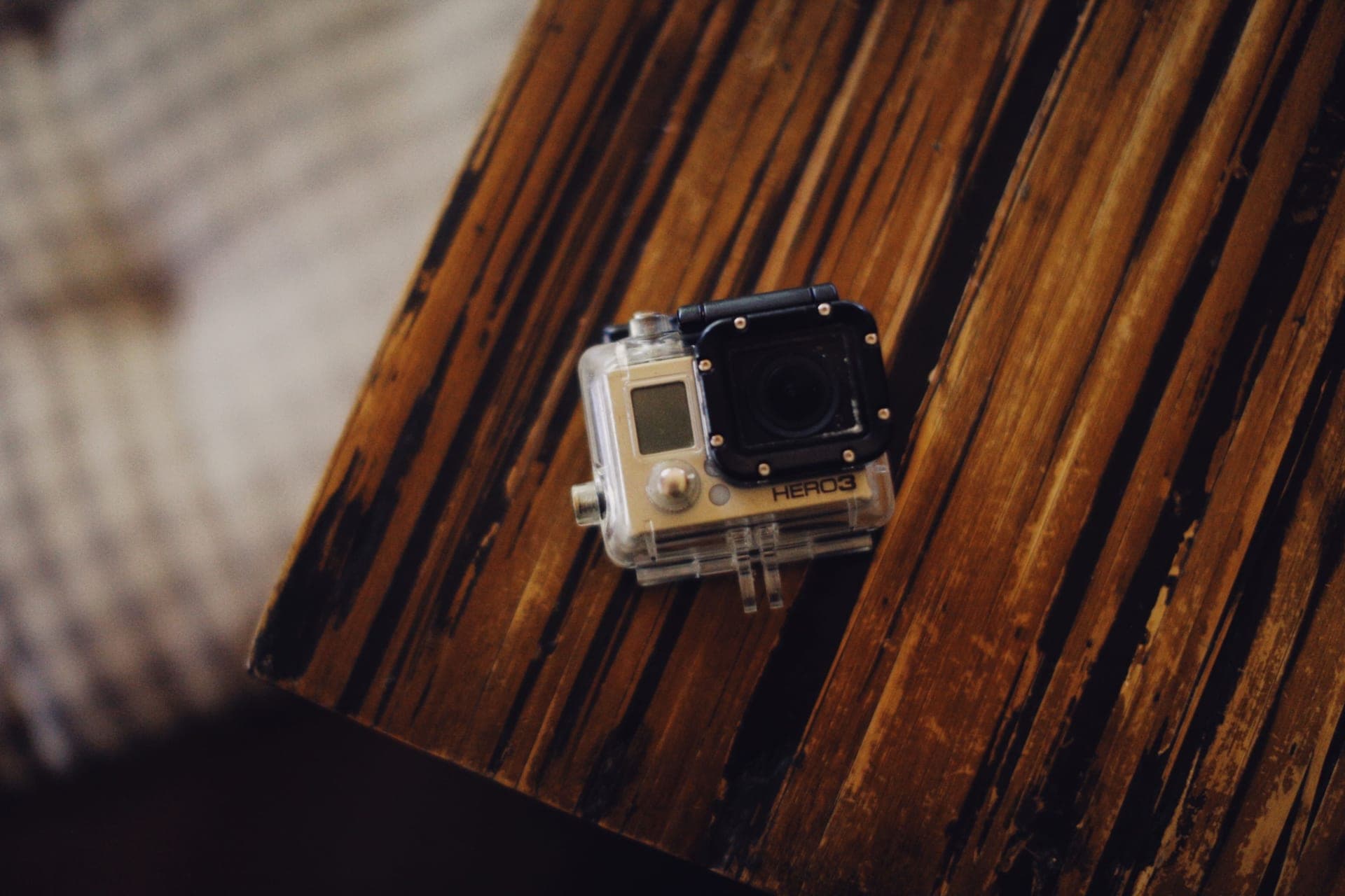 A compact action camera on a wooden table, showing its ports