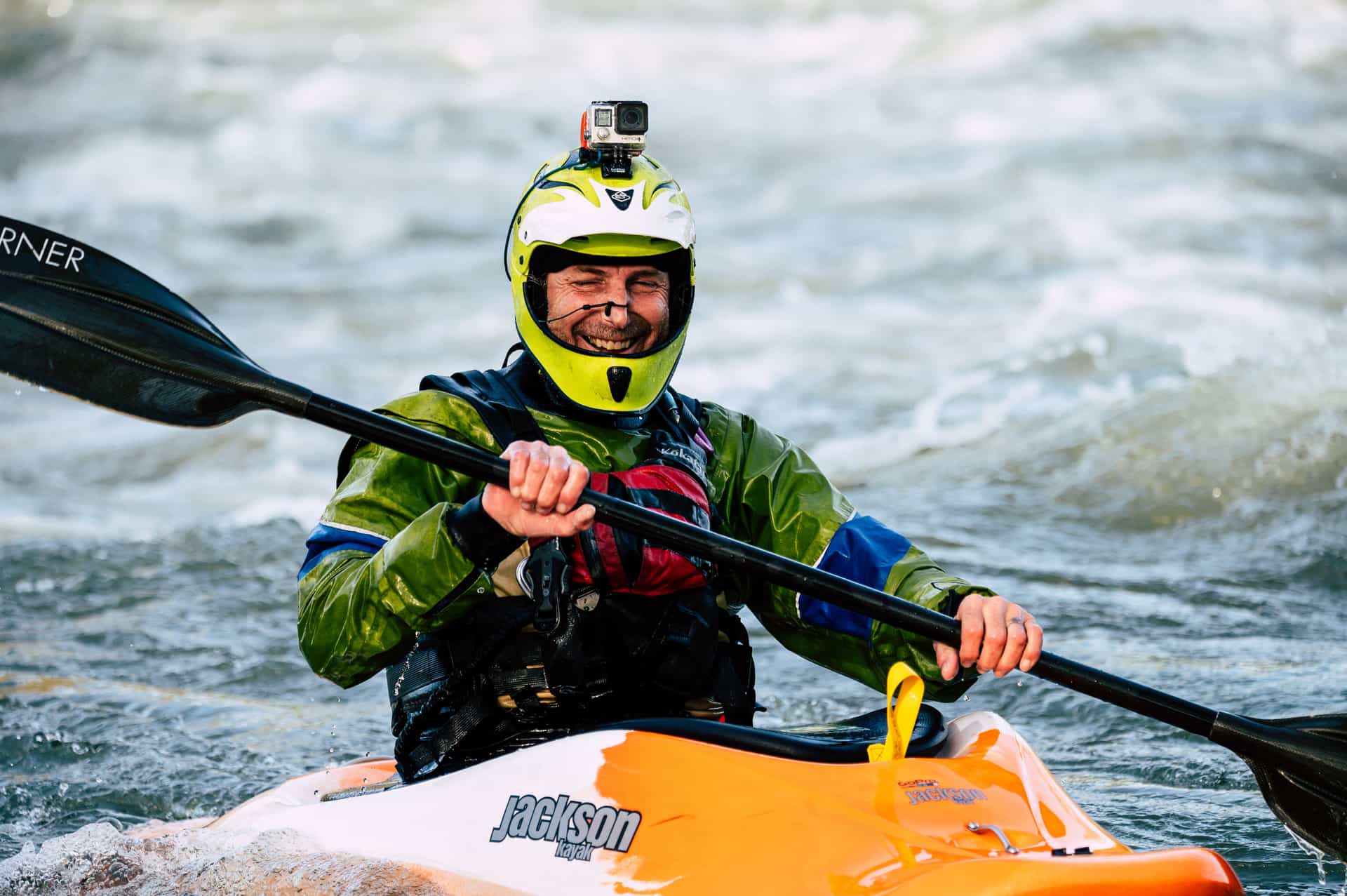 A kayaker in rapids, with an action camera mounted on their helmet
